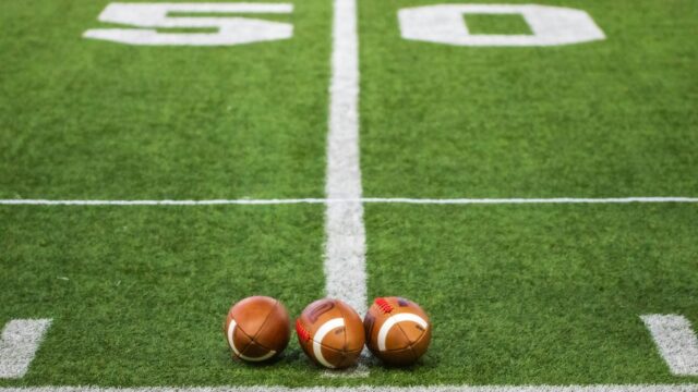 Three American footballs on a grass football field